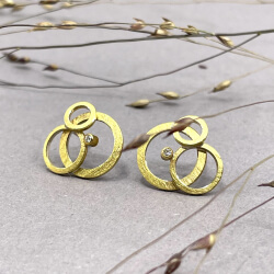 Die Ohrringe bestehen aus je drei unterschiedlich großen goldenen Kreisen. Ein kleiner Diamant ist der besondere Hingucker.