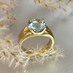 Breiter goldener Ring mit funkelndem blauem Stein