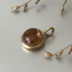 goldener anh&auml;nger mit bergkristall und roten nadeln