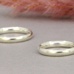 Zwei Trauringe "John und Yoko" gewölbt aus 925 Silber Bild 3 Zwei Trauringe in Platin liegen auf einem grauen Untergrund.